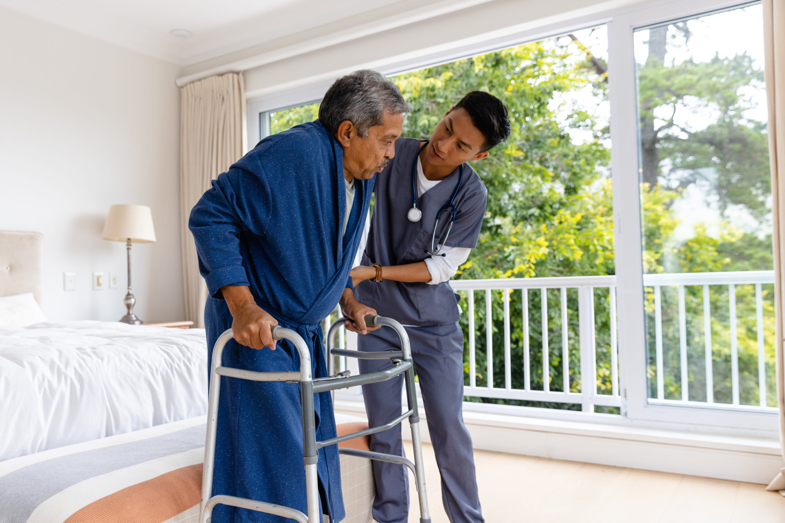 Diverse male doctor helping senior male patient using crutches at home. Medical services, check up, home visit, healthcare, wellbeing and senior lifestyle, unaltered.