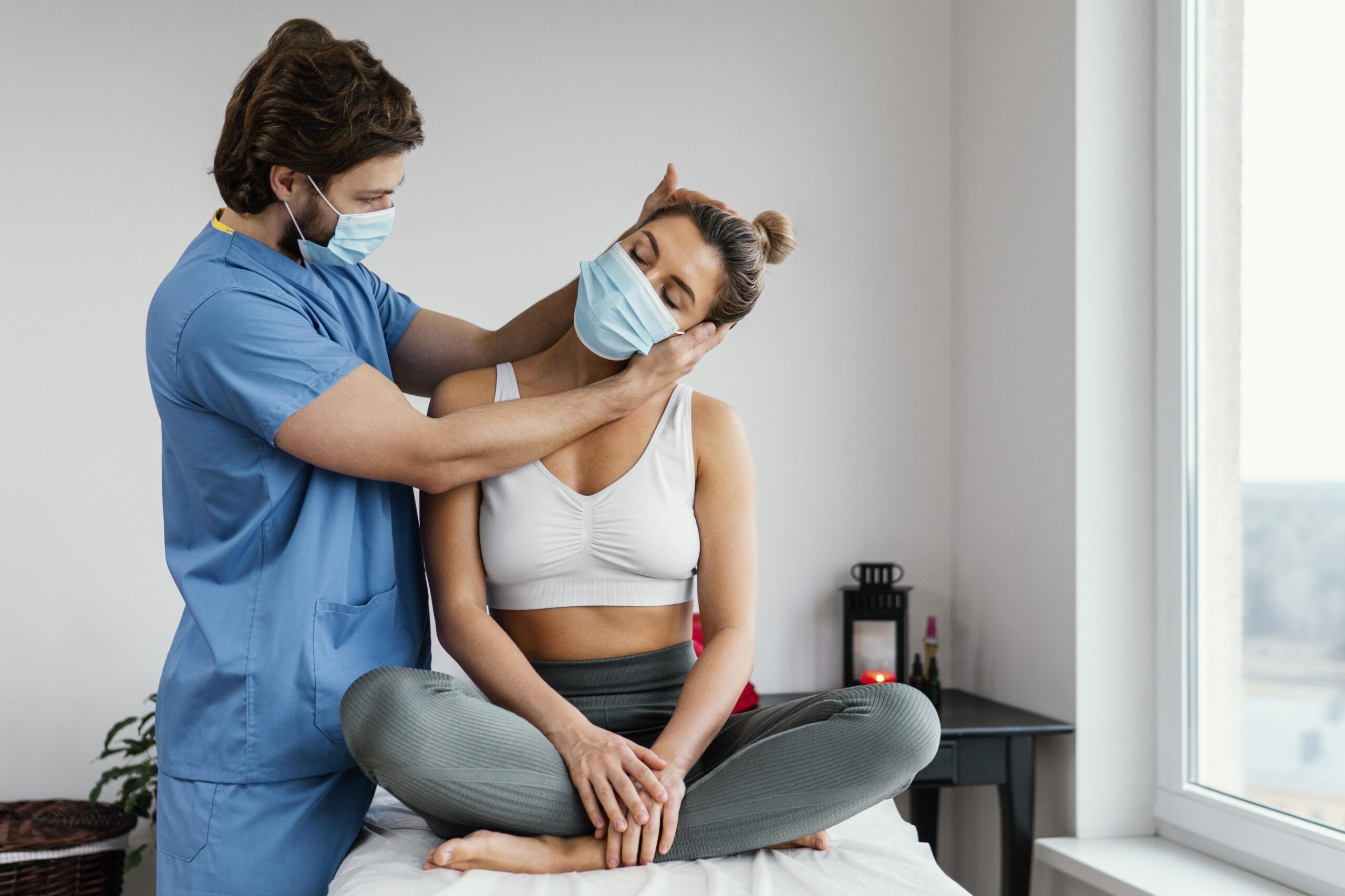 male-osteopathic-therapist-with-medical-mask-checking-female-patient-s-neck-muscles